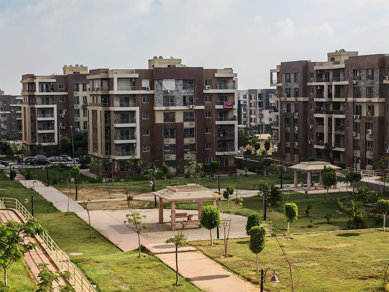 services-02 A modern apartment complex featuring green urban park with pathways and recreational structures.